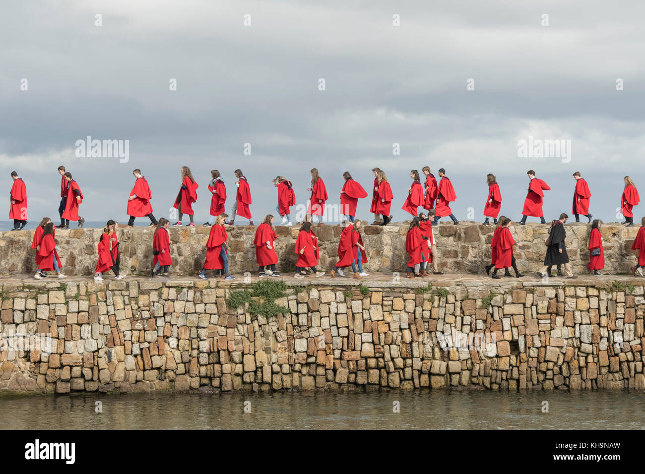 ST Andrews, Scozia-Settembre 17, 2017: studenti universitari da St Andrews University a piedi lungo il molo del porto a seguito di un servizio religioso Foto Stock