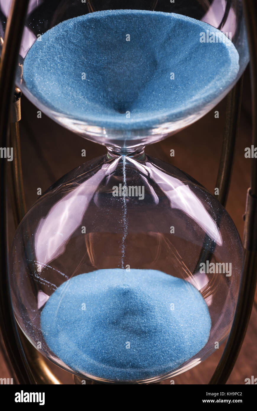 Clessidra con sabbia in colore blu e corpo in vetro bloccato dal telaio metallico. Foto Stock