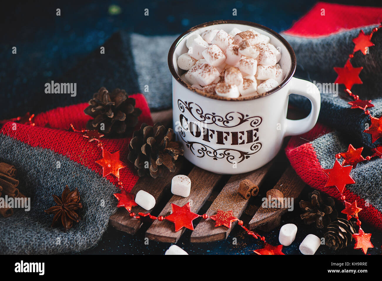 Natale cioccolata calda con marshmallows, cannella, sciarpa lavorata a maglia, stelle, pigne e festoni su un caldo sullo sfondo di legno Foto Stock