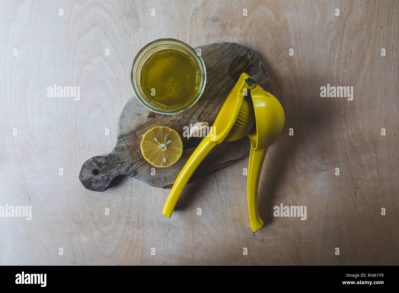 Semplice condimento per insalata ingredienti tra cui aglio, limone e olio di oliva insieme contro uno sfondo di legno Foto Stock