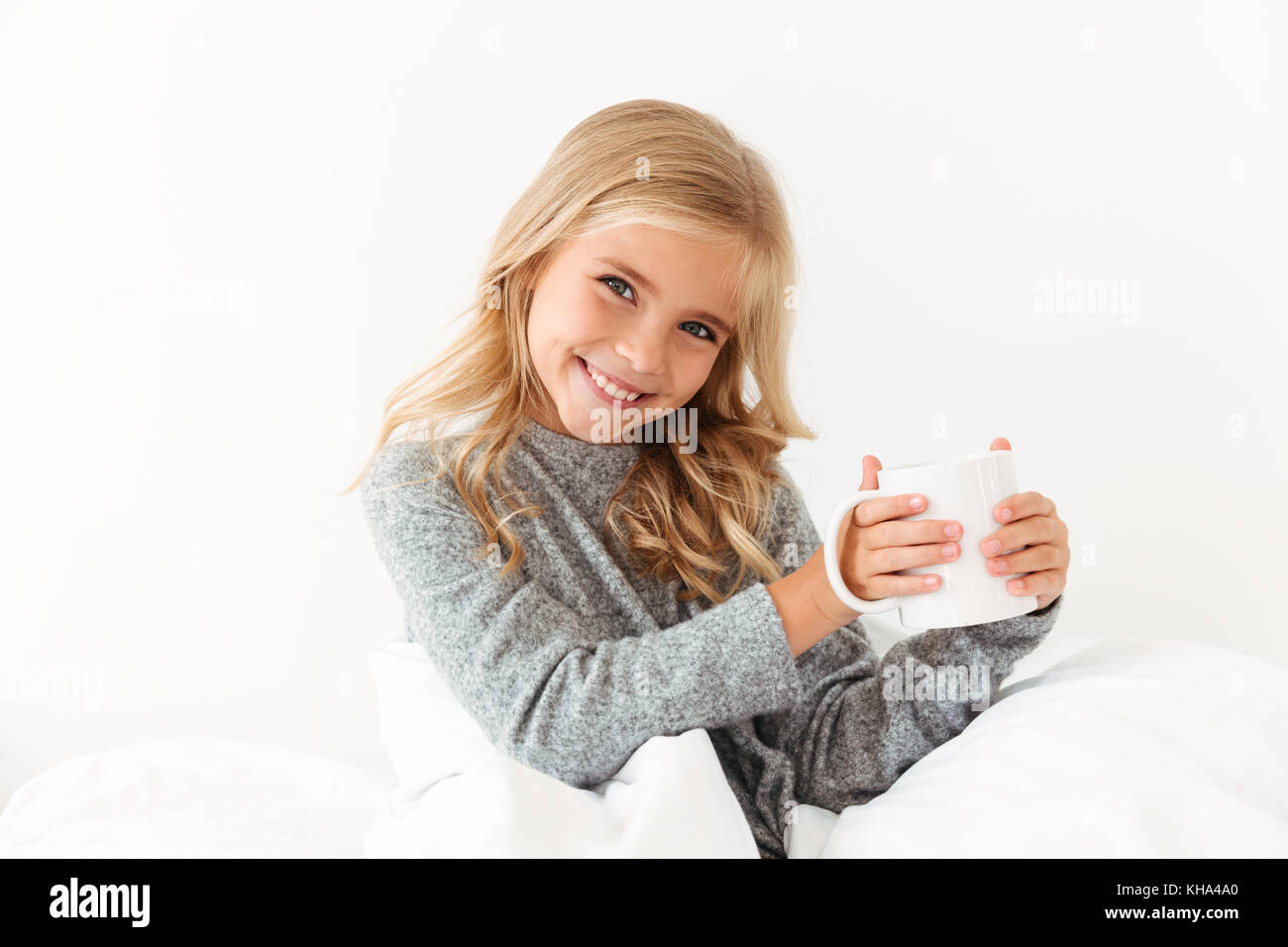 Allegro bambina coppa di ritegno del raccordo a T, guardando la fotocamera mentre è seduto nel letto Foto Stock