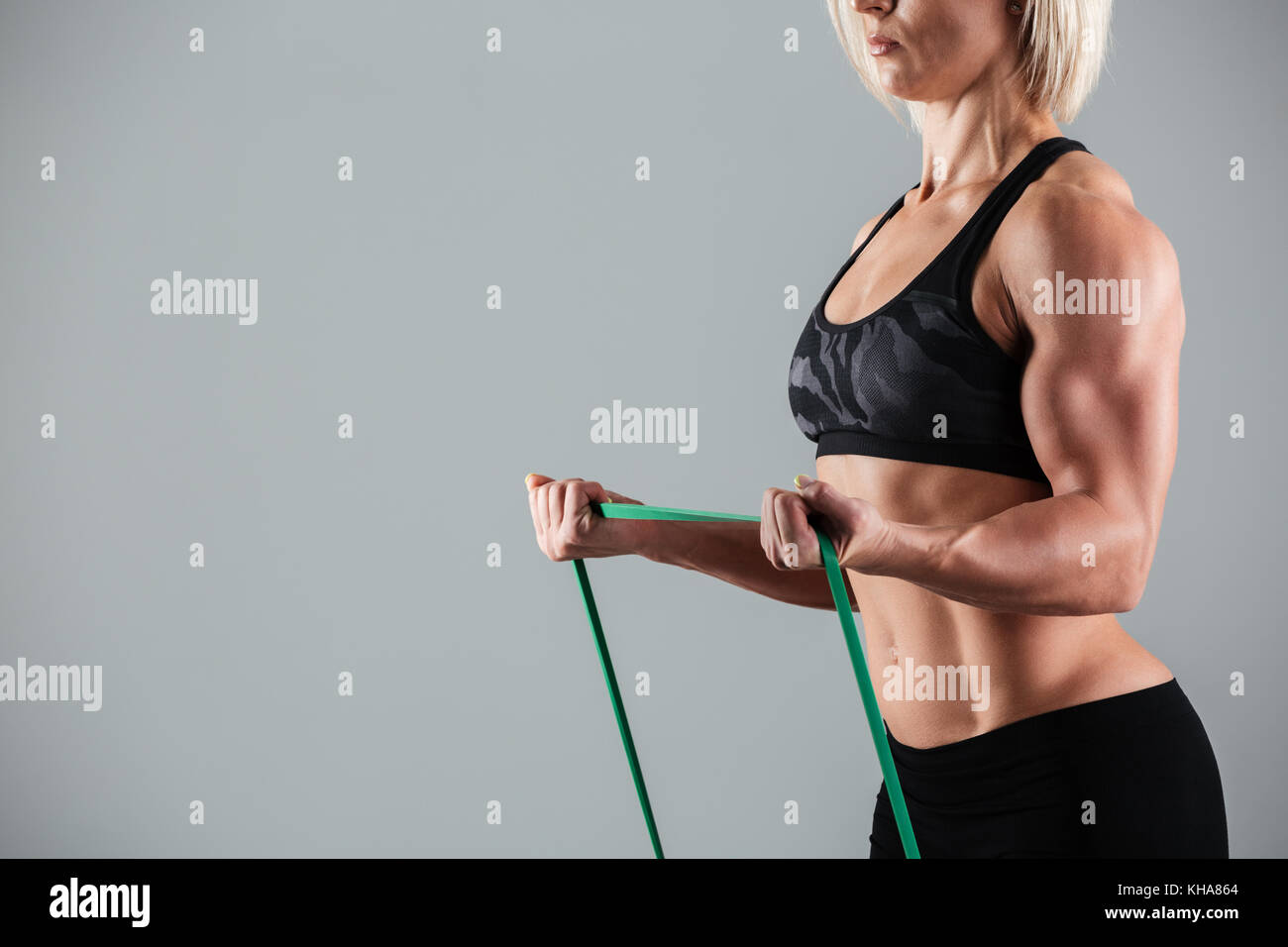 Foto ritagliata di bodybuilder femminile stretching con gomma elastica, isolati su sfondo bianco Foto Stock