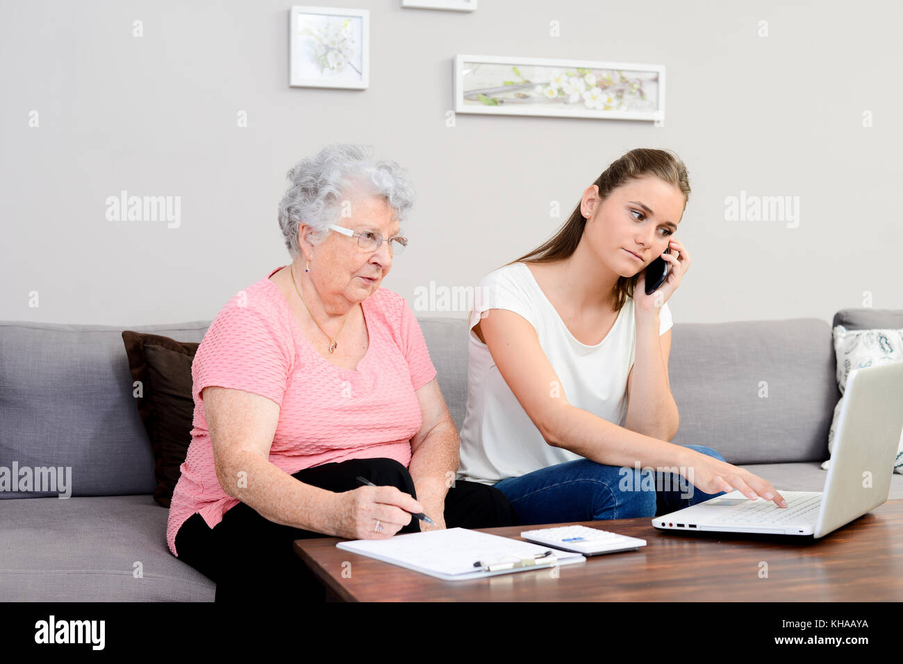 Allegro giovane donna aiutando vecchia persona facendo di documenti cartacei e telefonate. Foto Stock