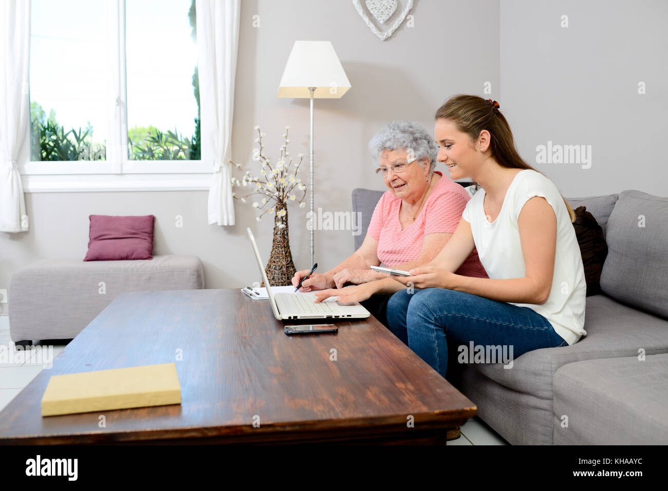 Allegro giovane donna aiutando vecchia persona facendo di documenti cartacei e telefonate. Foto Stock