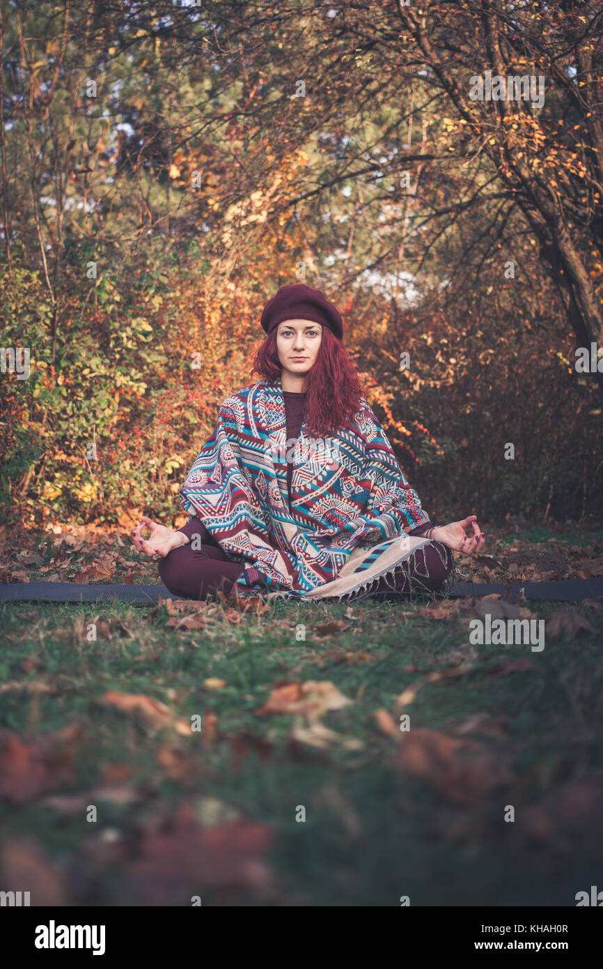 Ragazza di una luminosa giornata autunnale a praticare yoga all'aperto, seduta in facile (decente, piacevole) pongono (sukhasana) Foto Stock