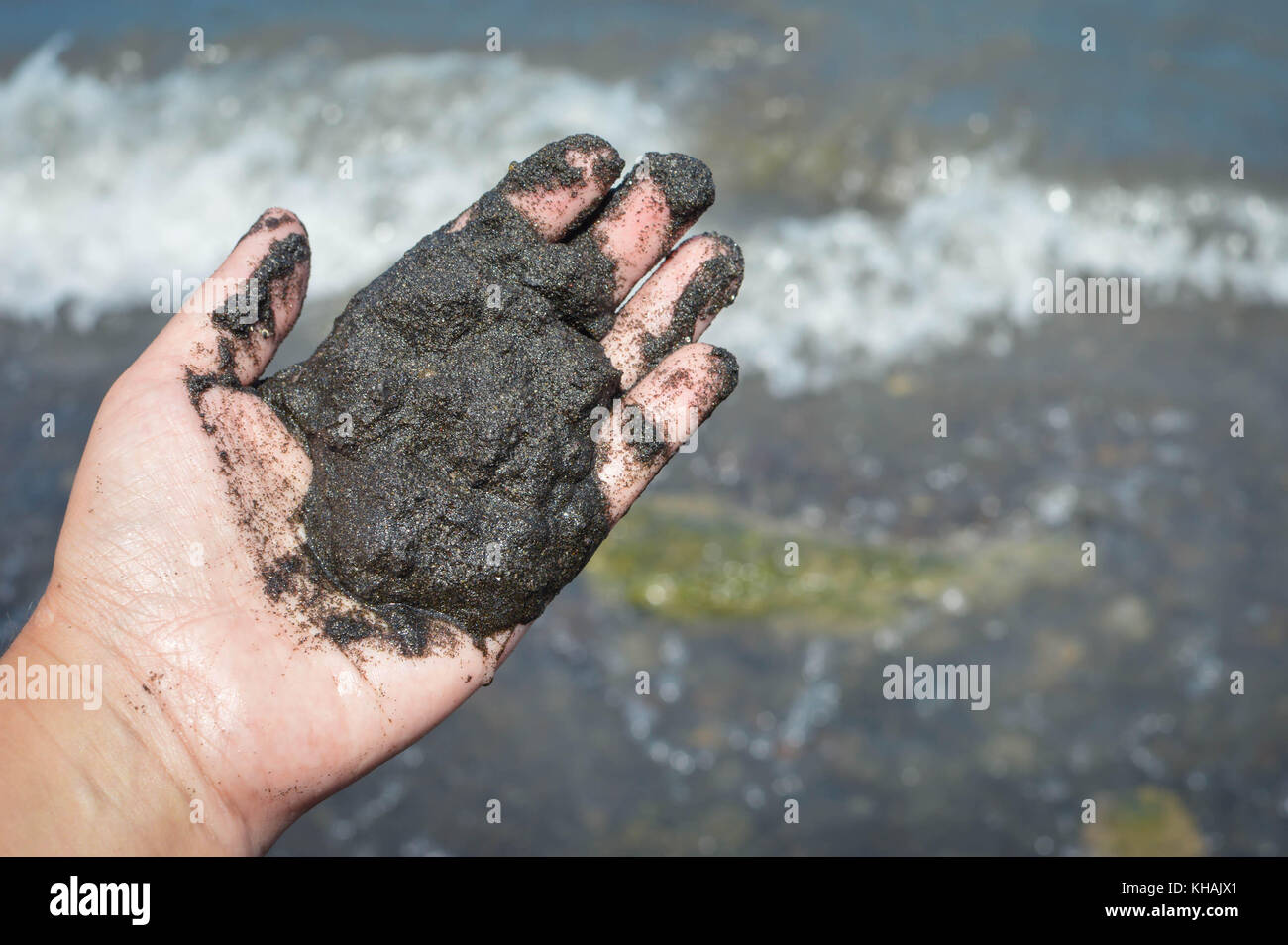 La mano trattiene sabbia nera vulcanica da spiaggia della caldera vulcanica Lago Laguna de Apoyo nelle highlands vicino a Masaya, Nicaragua. America centrale Foto Stock