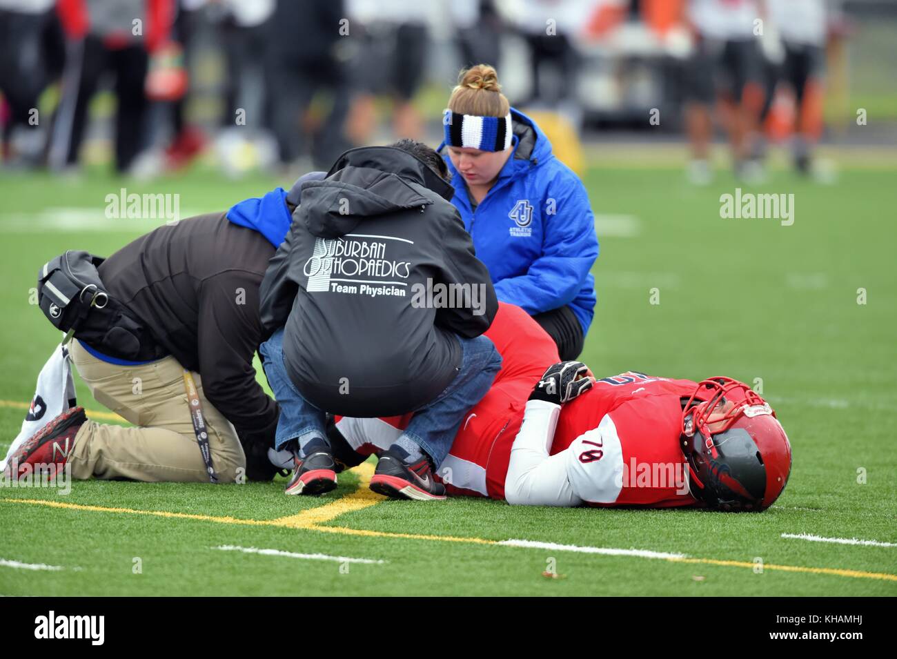 Feriti giocatore di calcio che viene trattata sul campo mediante la formazione e il personale medico. Stati Uniti d'America. Foto Stock