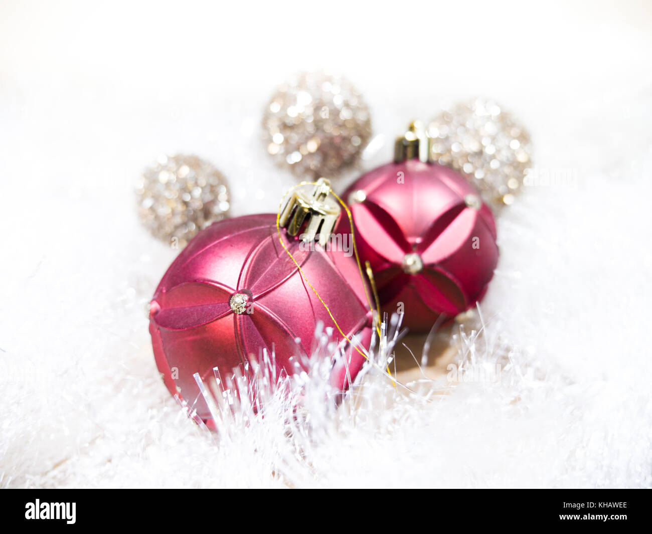 Bella vicino la fotografia di rosso, oro e argento Ornamenti natale posa su bianco scintillante garland facendo una vacanza fantastica immagine di sfondo. Foto Stock