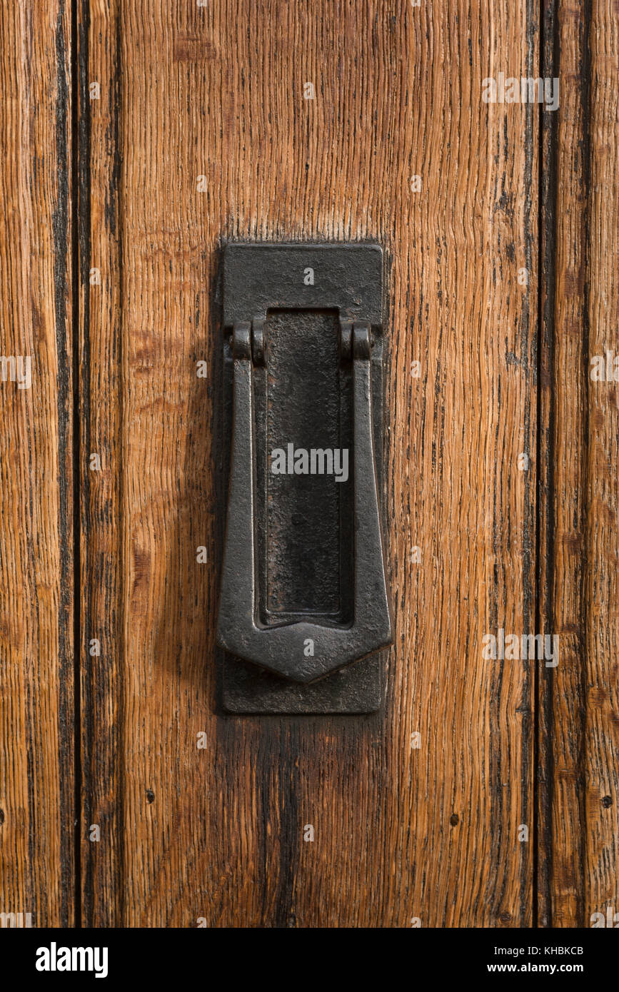 Un sostanziale di ghisa nera, porta combinata respingente & letterbox montato su un vecchio, la linguetta e scanalatura oak porta anteriore. Foto Stock
