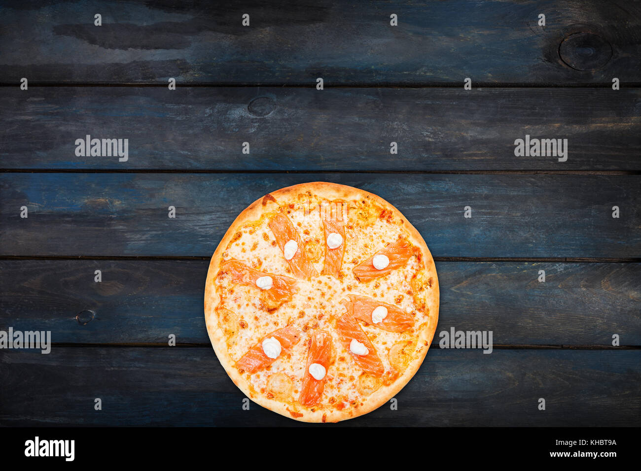 Una deliziosa pizza con salmone e formaggio Filadelfia sul legno scuro dello sfondo. vista superiore di orientamento di fondo. Foto Stock