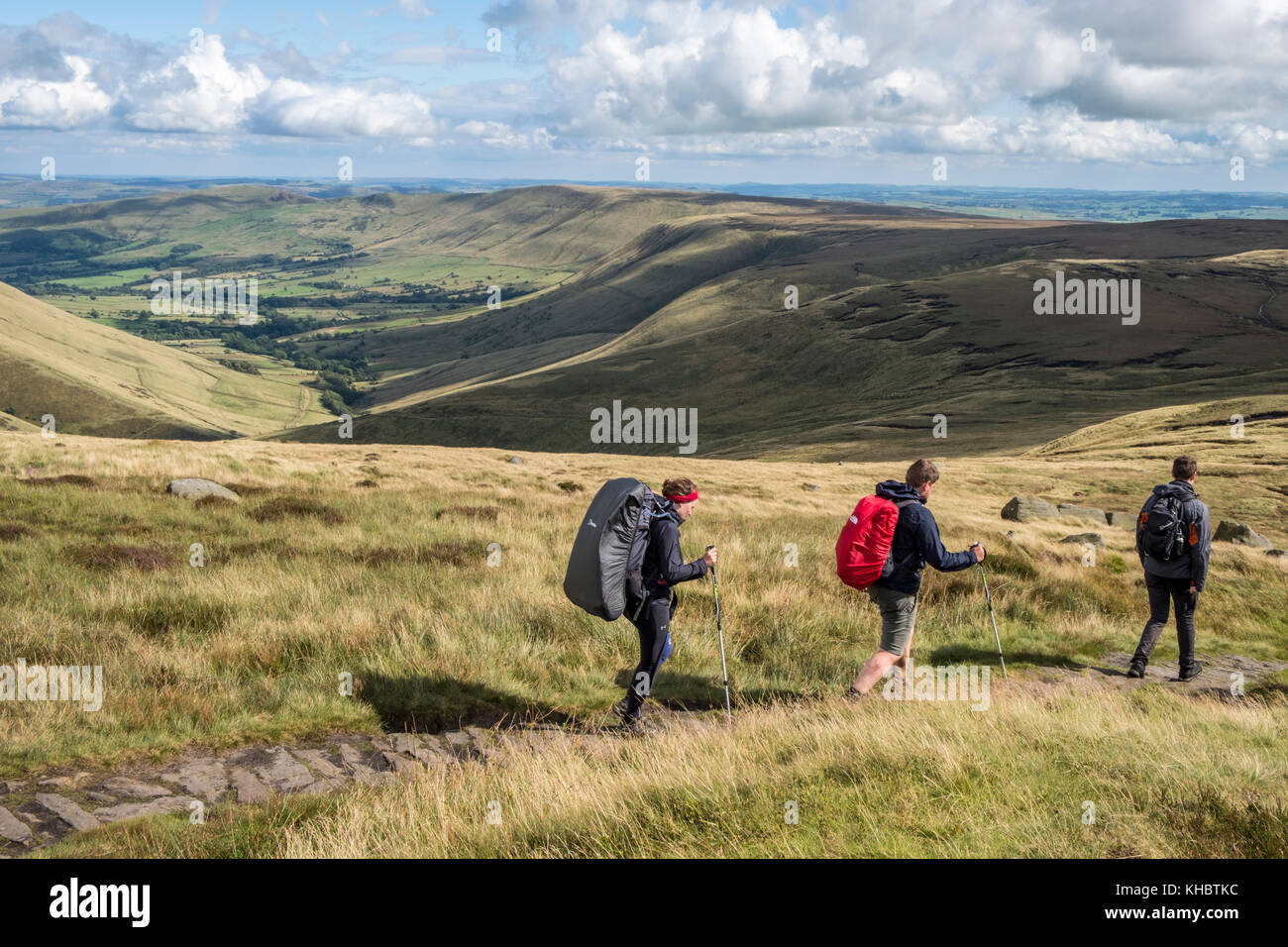Walkers su un sentiero brughiera nel Peak District campagna con la valle di Edale a distanza. Kinder Scout, Derbyshire, England, Regno Unito Foto Stock