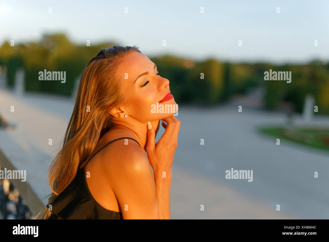 Giovane romantico donna sogna a occhi chiusi nel tramonto, all'aperto Foto Stock