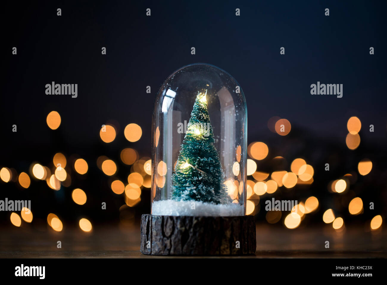 Festive albero di Natale all'interno di un vetro snowglobe con luci sfocate Foto Stock