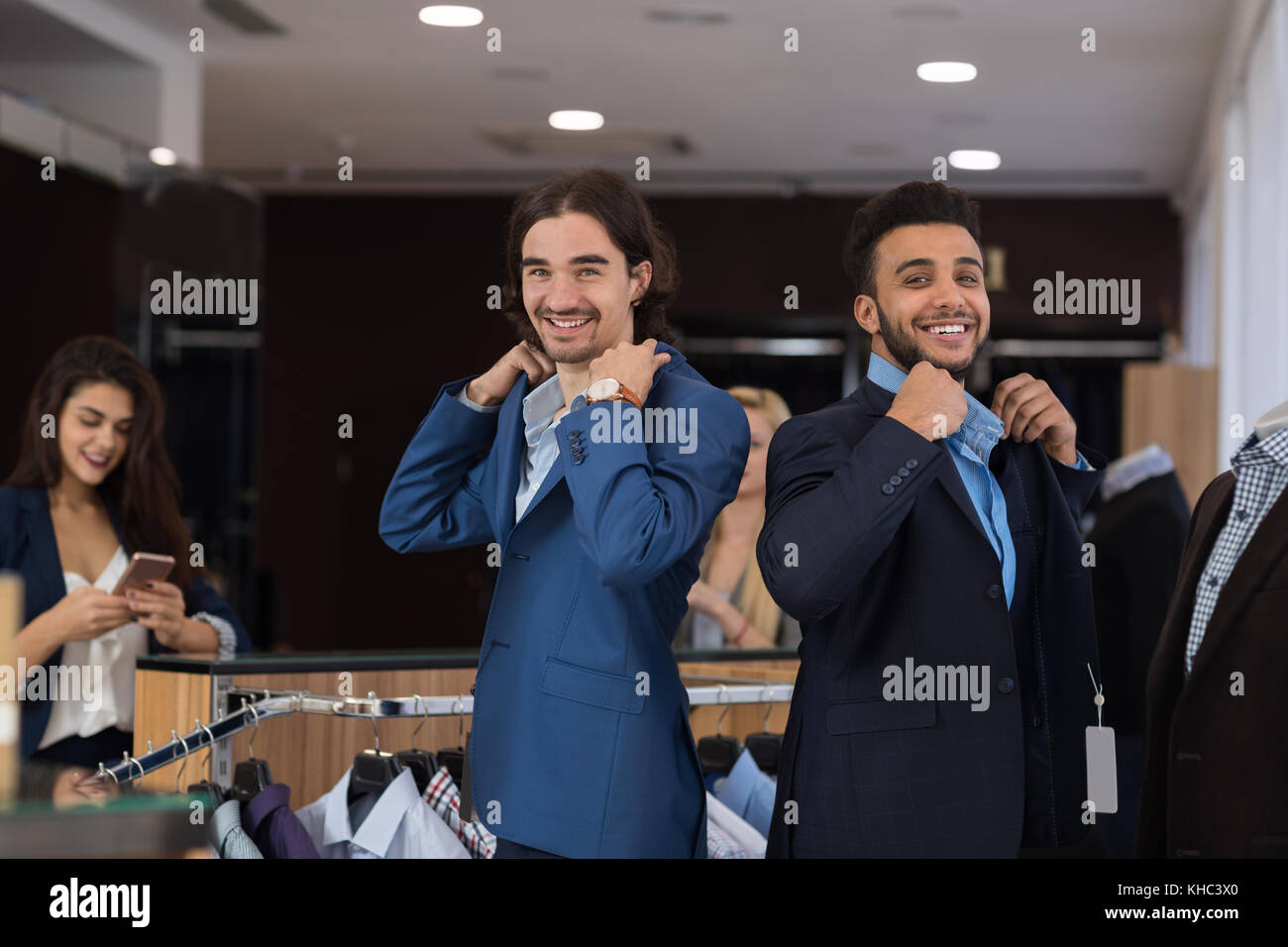 Due business belli gli uomini indossano tute di nuovo mentre lo shopping nei moderni menswear store Foto Stock