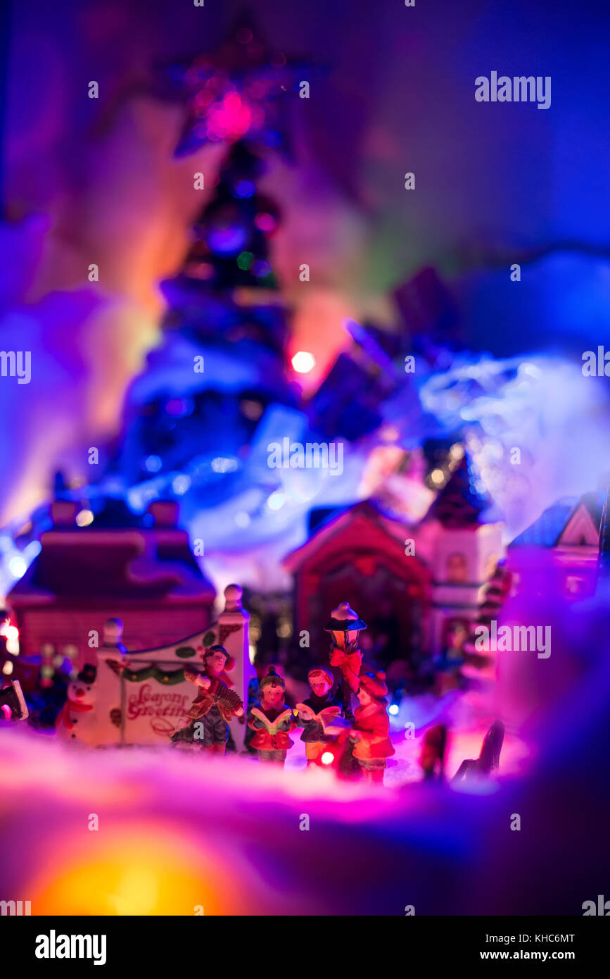 'Seasons saluto con bambini cantando vangelo con colorato villaggio natale sfocato in background. vacanza festosa miniatura ' Foto Stock