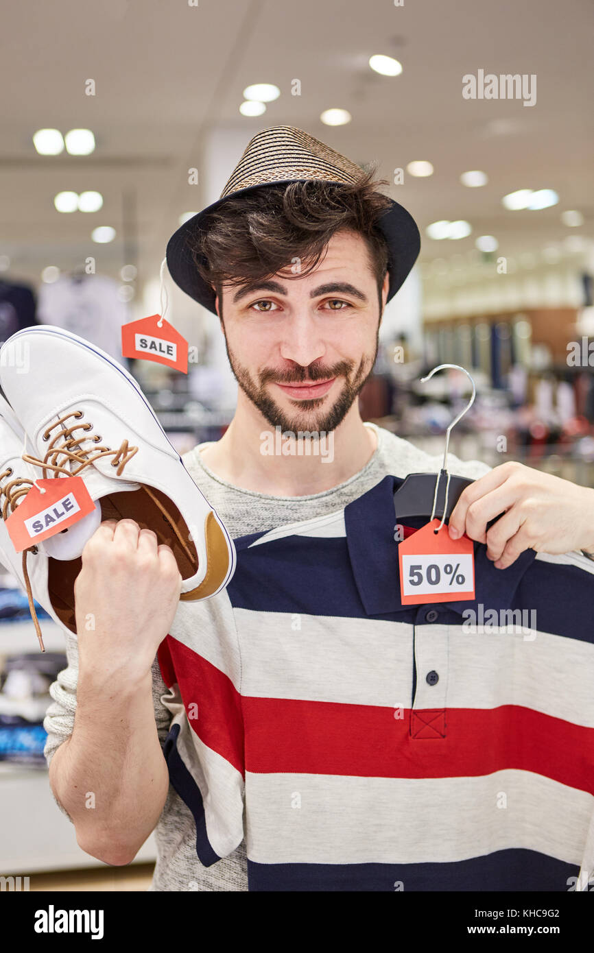 Giovane uomo trova shopping fashion a prezzo promozionale in negozio alla moda Foto Stock