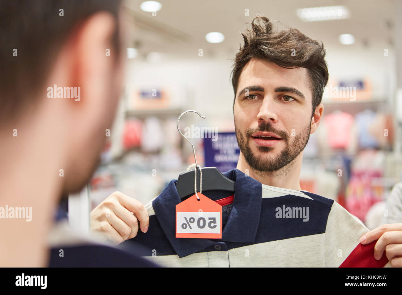 Giovane uomo in shopping fashion sta cercando una camicia in negozio alla moda Foto Stock