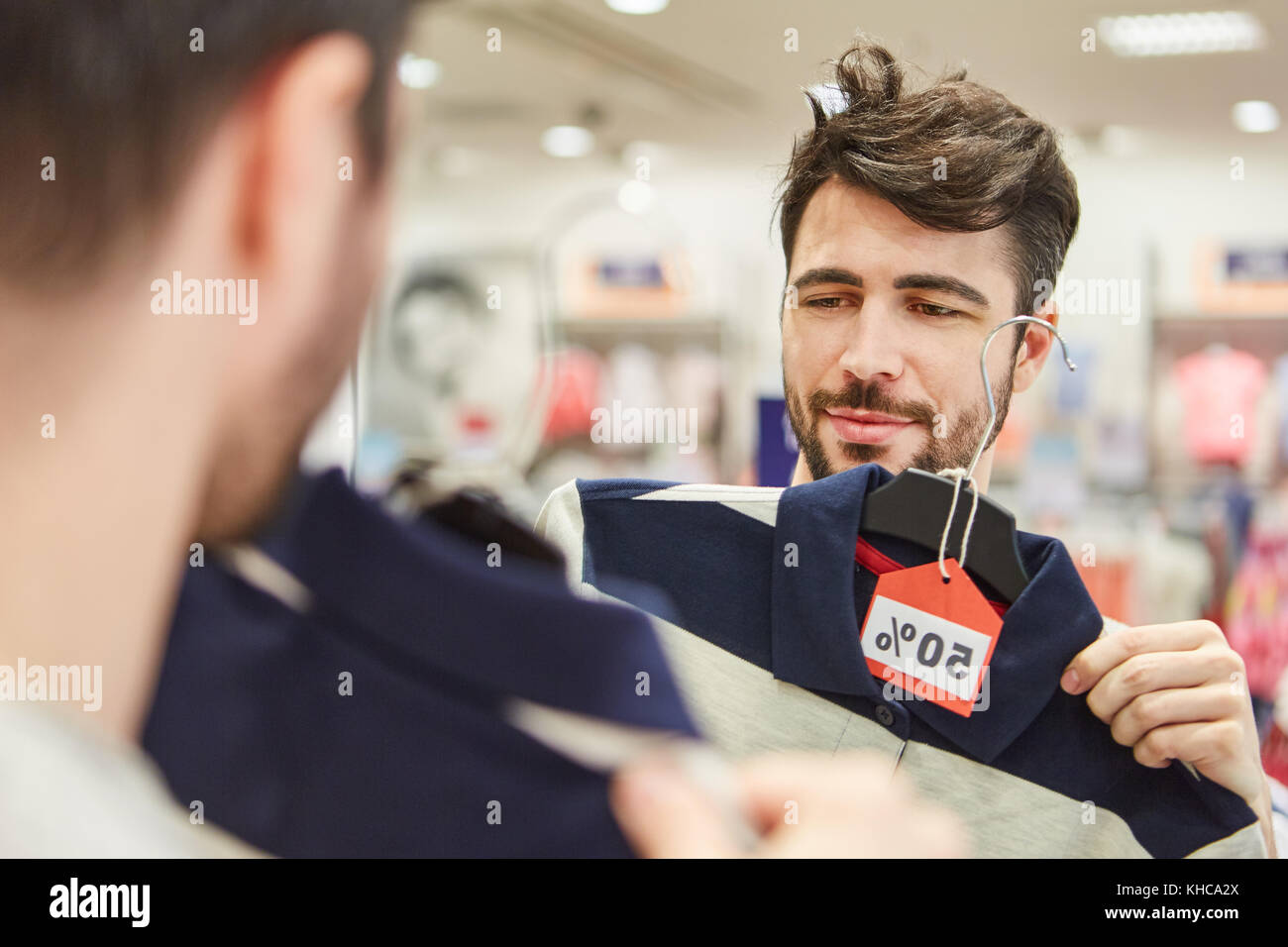 Giovane uomo moda per lo shopping di fronte allo specchio nel negozio di sconto Foto Stock