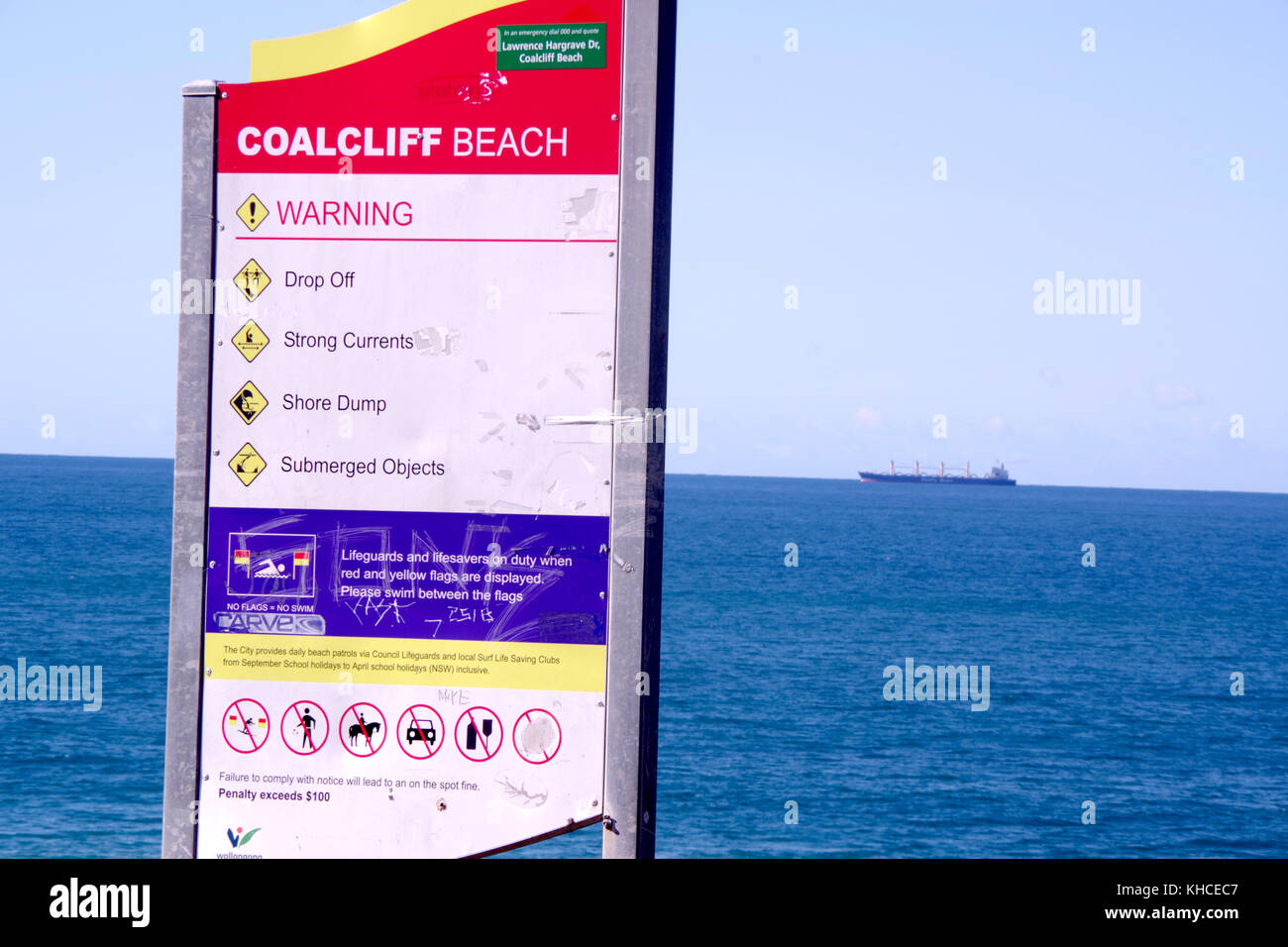 Un cartello che elenca informazioni, avvertenze e informazioni proibitivo per coalcliff beach, coalcliff, Nuovo Galles del Sud, Australia. una nave passa dietro. Foto Stock