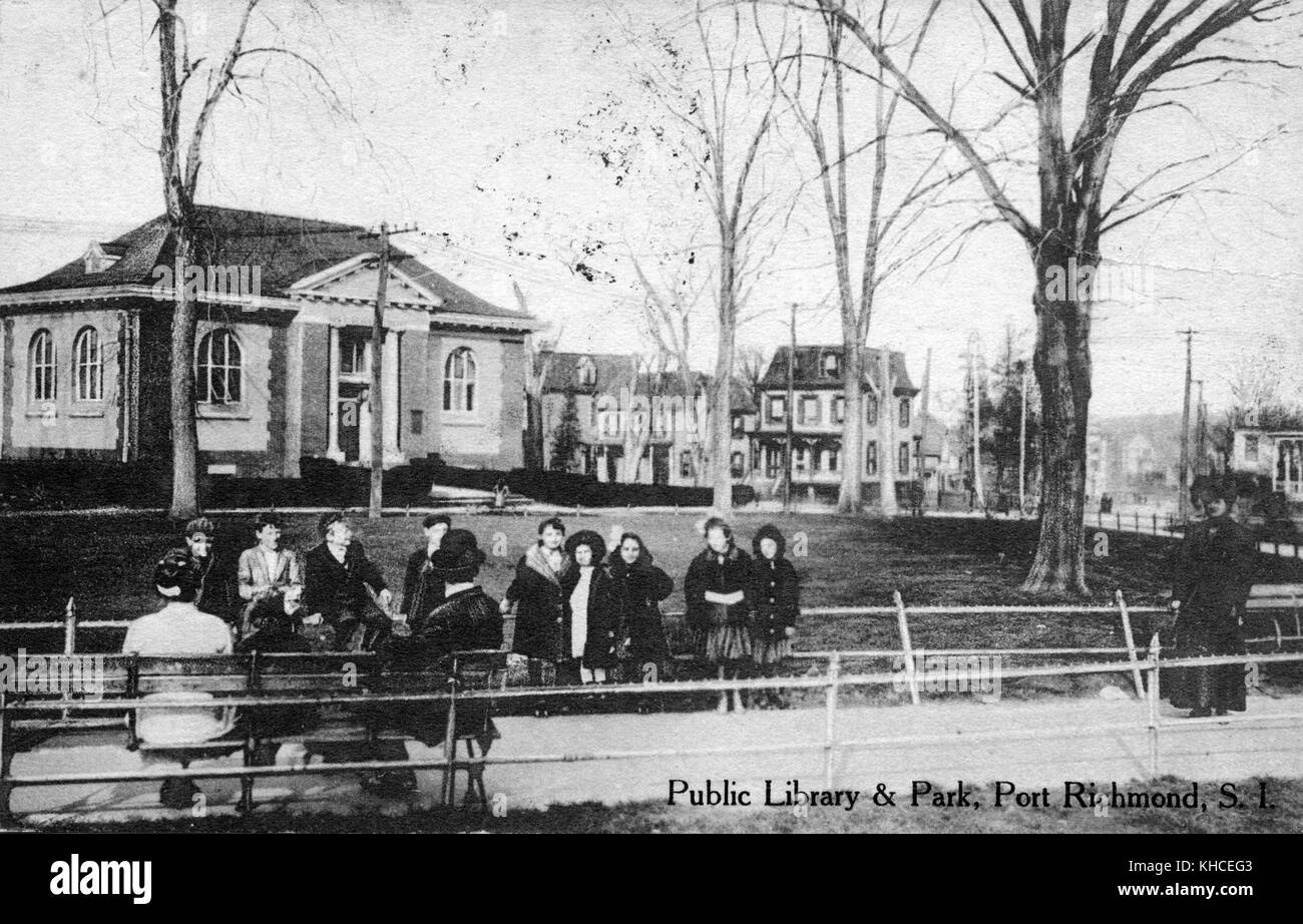 Una cartolina da una fotografia di una biblioteca pubblica e di un parco, la biblioteca e l'alloggio residenziale possono essere visti al lato lontano del parco, un gruppo di uomini, donne e bambini siedono su panchine lungo un sentiero in primo piano, Port Richmond, Staten Island, New York, 1900. Dalla Biblioteca pubblica di New York. Foto Stock