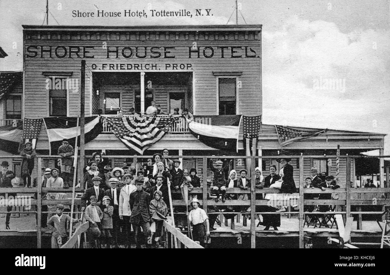 Una fotografia dell'esterno dello Shore House Hotel, un grande gruppo di persone sono raccolti il ponte per posare per la fotografia, l'hotel è stato coperto con bandiere, un uomo d'affari del New Jersey ampliato un hotel preesistente per ospitare la popolarità delle spiagge nella zona, Tottenville, state Island, New York, 1900. Dalla Biblioteca pubblica di New York. Foto Stock