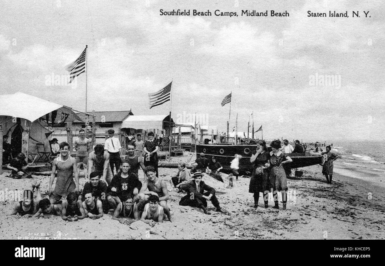 Cartolina di persone nei costumi da bagno dei primi del 20 ° secolo su sabbia, barca a vela, cottage e bandiere, intitolato Southfield Beach Camps, Midland Beach Staten Island, New York, pubblicato da MM Schaffer e Son, Staten Island, New York, 1900. Dalla Biblioteca pubblica di New York. Foto Stock