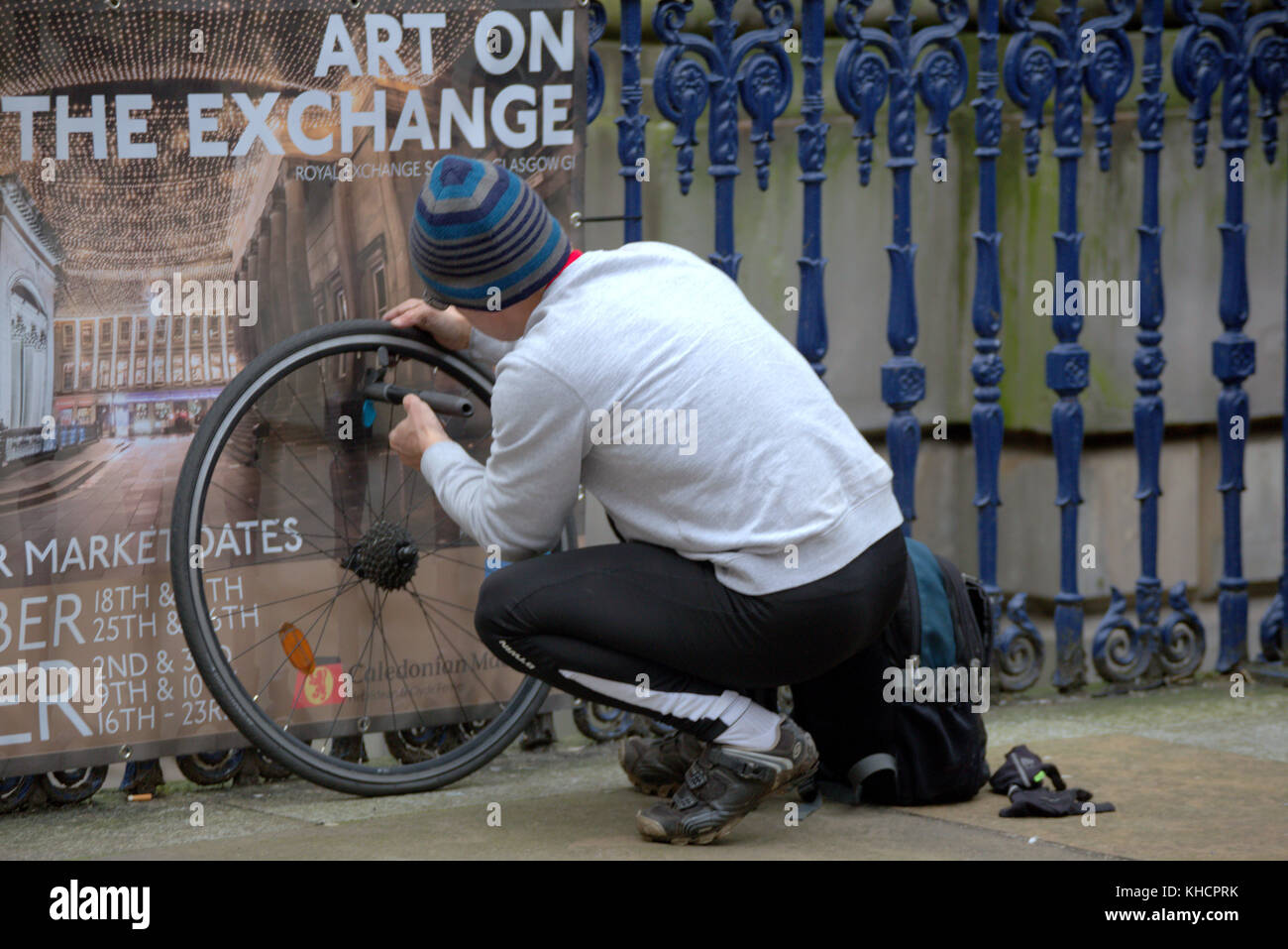 Ciclista la riparazione di una bicicletta puntura nella royal exchange square glasgow goma Foto Stock