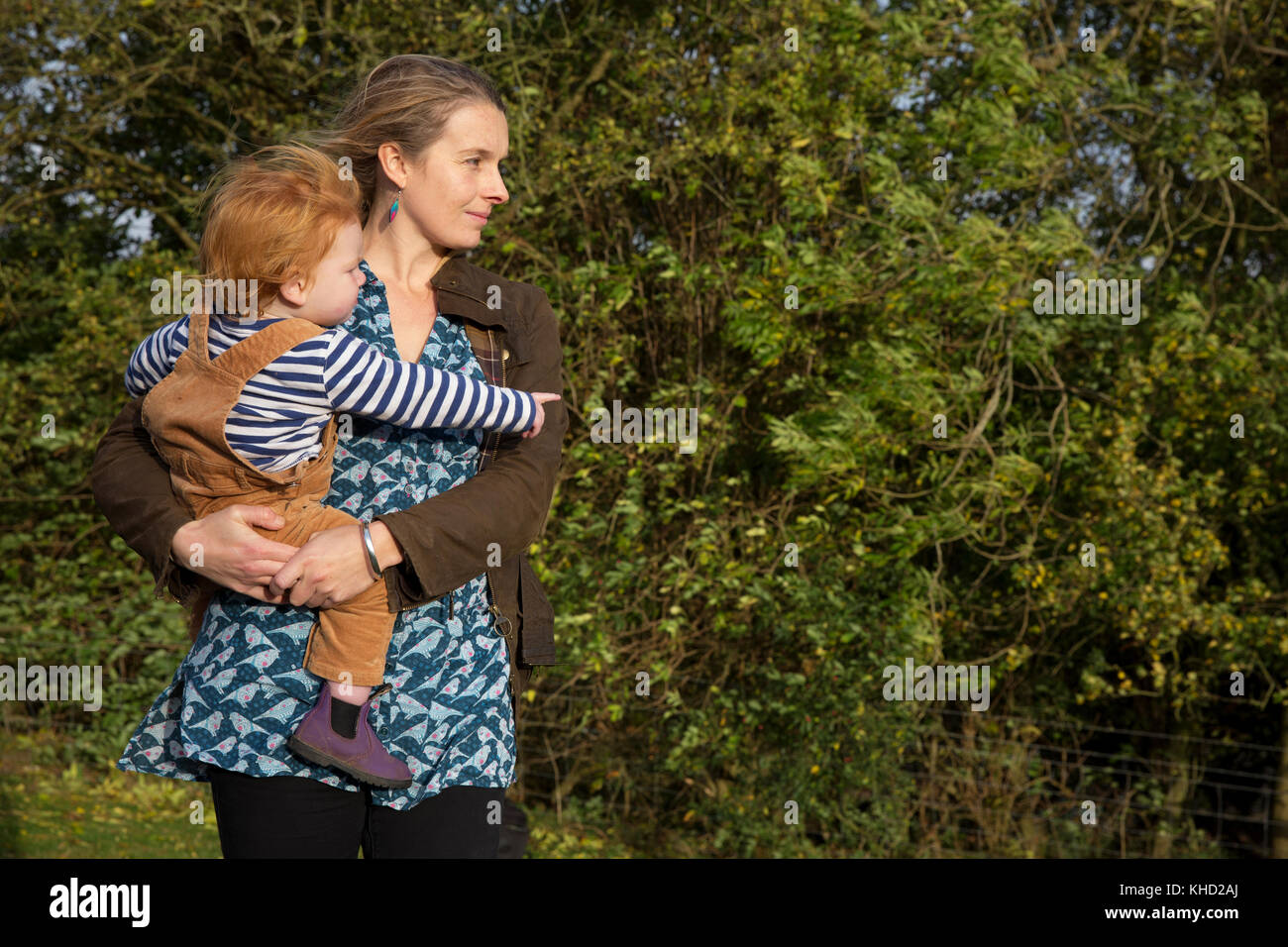 Donna che trasportano il toddler figlio di armi, puntano ad alberi Foto Stock