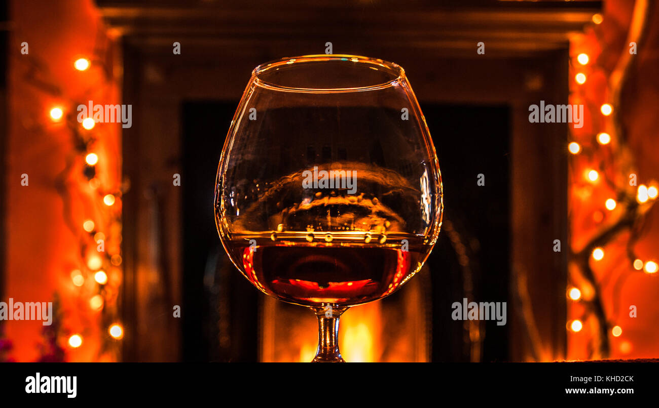 Un bicchiere di brandy riscaldato da un accogliente caminetto in inverno. Foto Stock