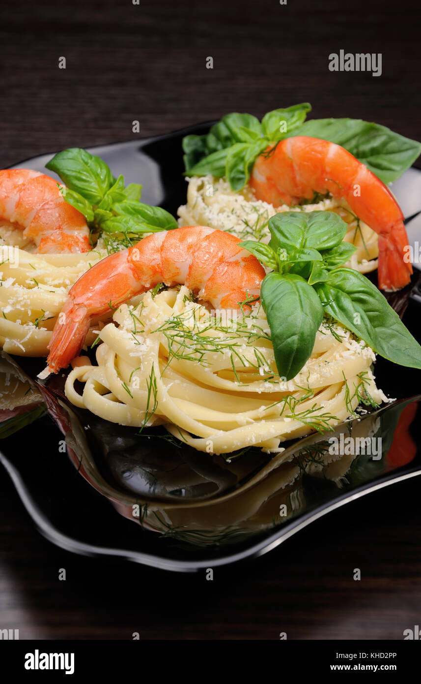 Nidi di spaghetti con parmigiano aromatizzato con aneto, gamberi e basilico. Foto Stock