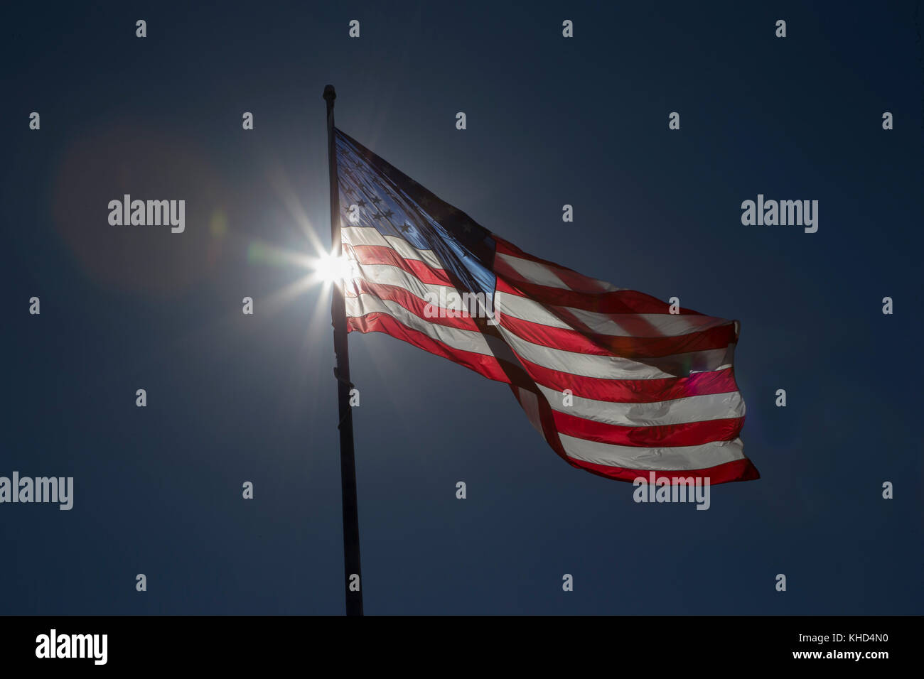 Bandiera americana retroilluminazione contro un profondo cielo blu Foto Stock