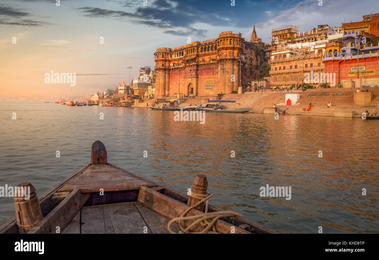 Varanasi gange fiume ghat con antichi edifici architettonici e templi come visto da una barca sul fiume al tramonto. Foto Stock