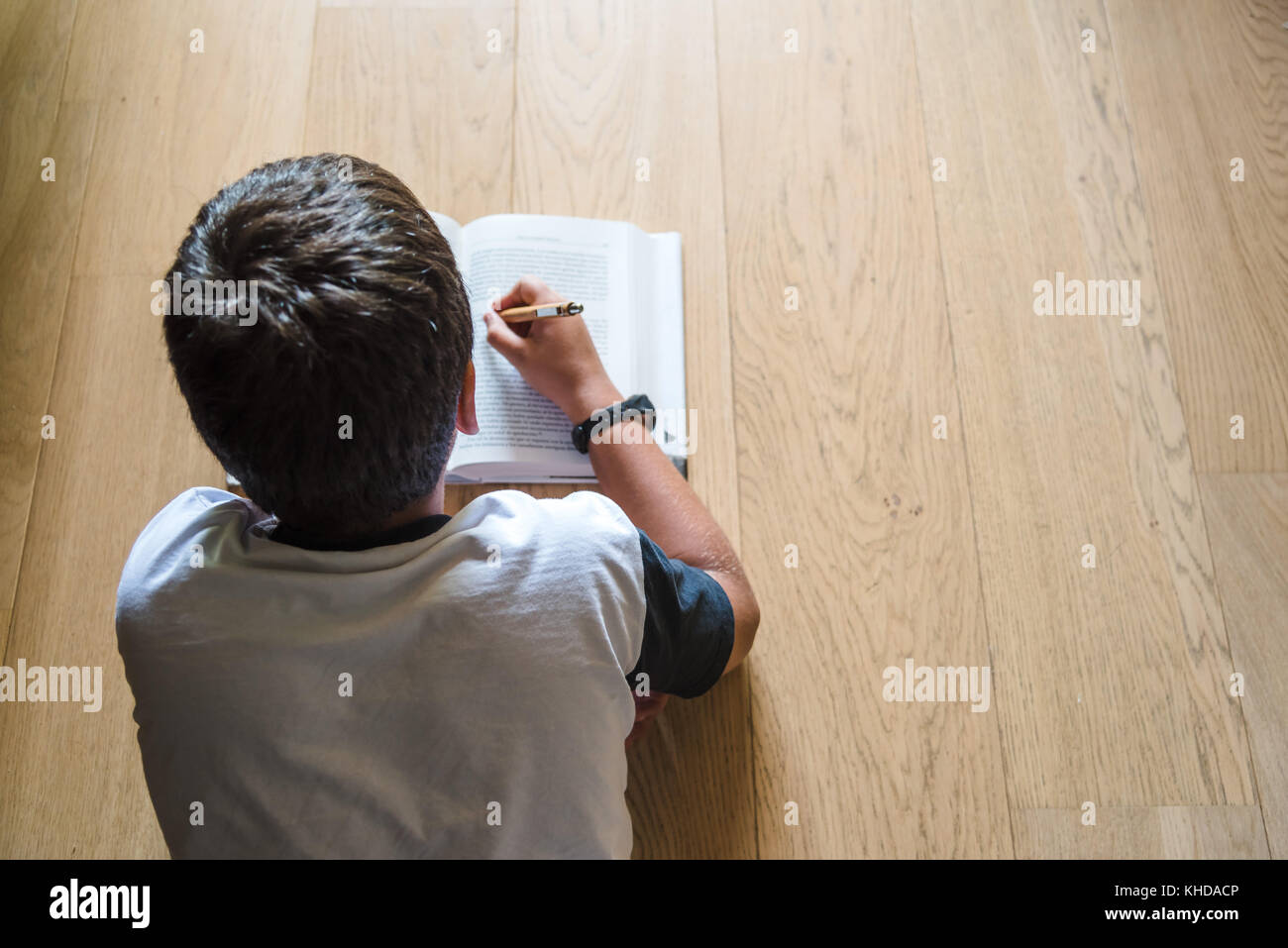 Little Boy bambino la lettura di un libro. Egli giace sul pavimento. Foto Stock