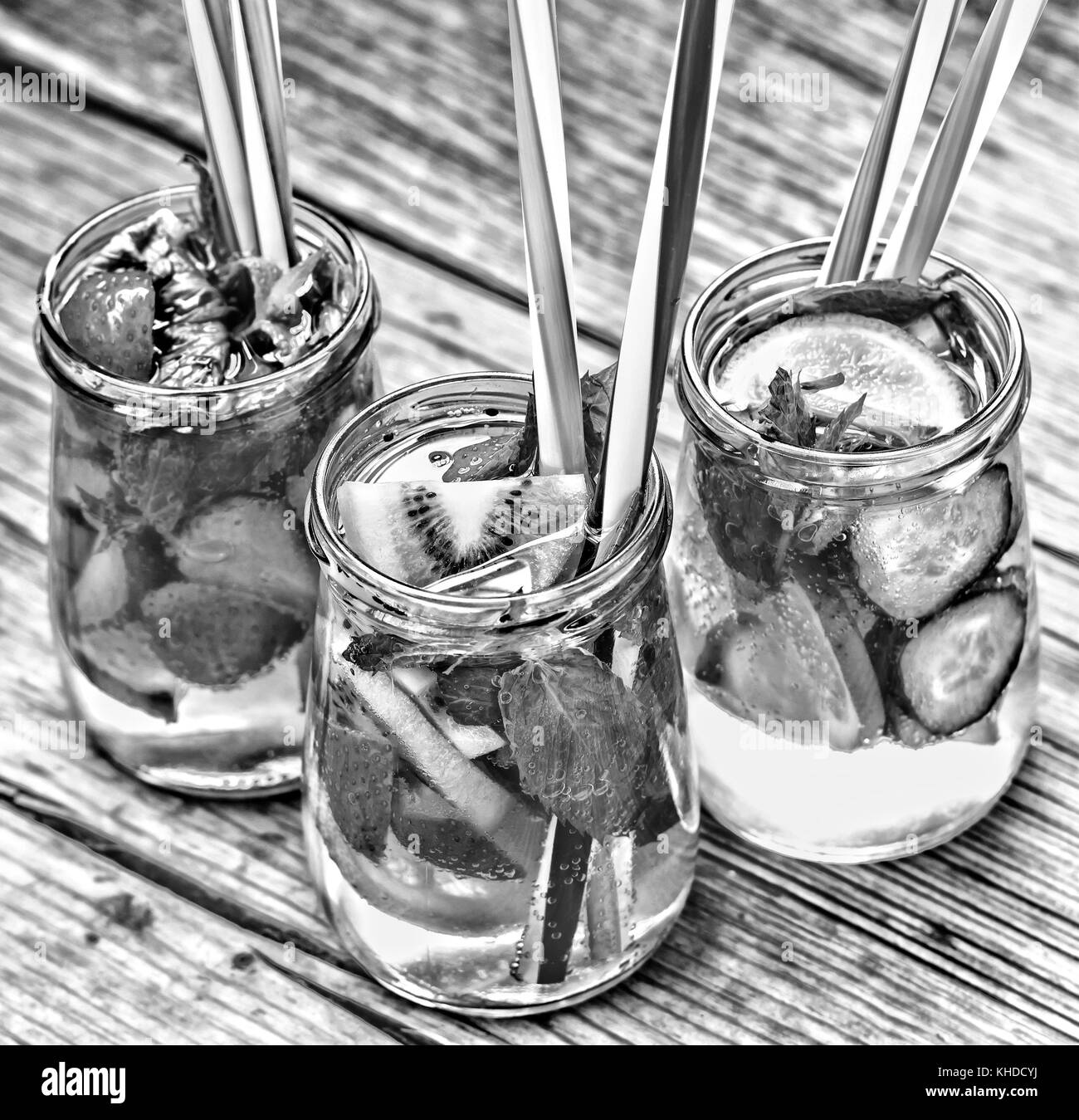 Una varietà di bevande fredde in piccoli flaconi con pezzi di frutta sullo sfondo di legno. close up Foto Stock