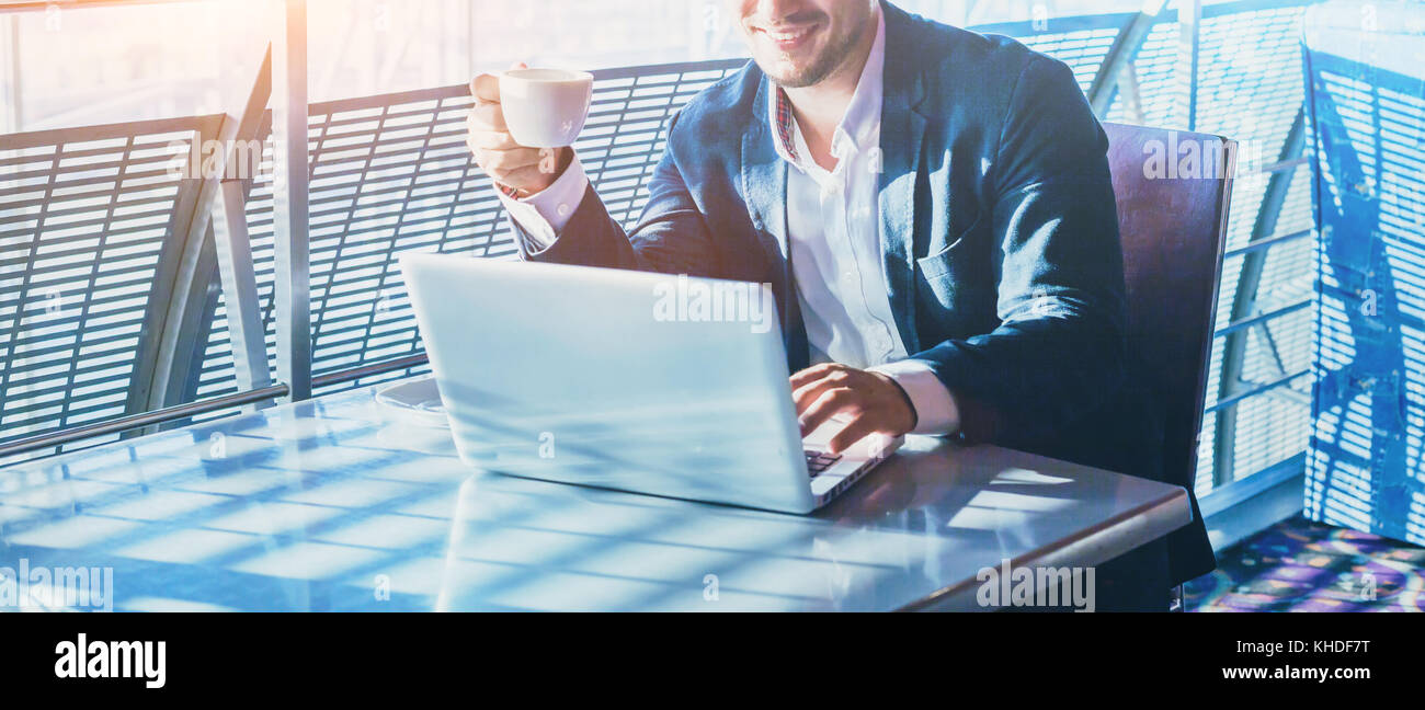 Imprenditore lavora su computer, a bere caffè e sorridente, astratto banner aziendale lo sfondo con il posto per il testo Foto Stock