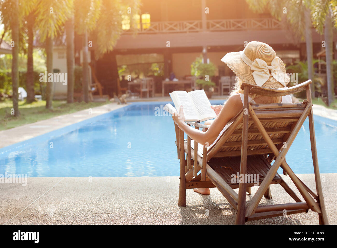 Concetto di rilassamento, donna libro lettura vicino alla piscina dell'hotel Foto Stock