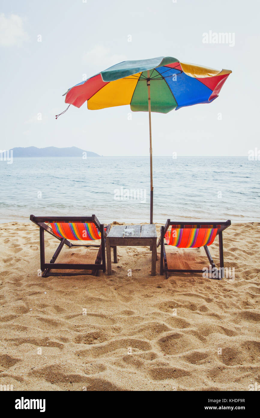 Spiaggia in Thailandia, due sedie a sdraio e ombrello coloratissimo vicino  al mare Foto stock - Alamy