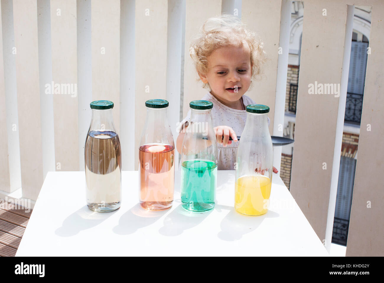 Bambina di suoni toccando le bottiglie di acqua Foto Stock