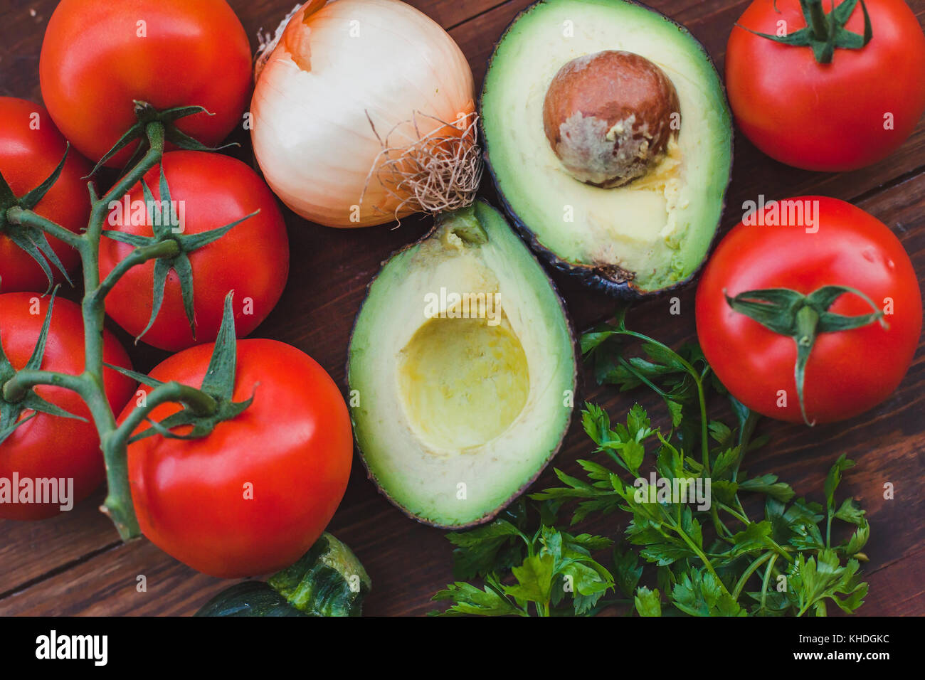 Avocado con pomodoro e cipolla su sfondo di legno, verdure fresche close up Foto Stock