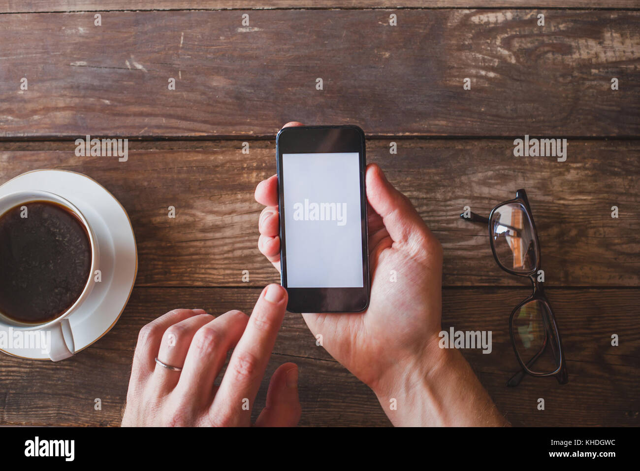 Mano azienda smart phone con vuoto schermo bianco su sfondo di legno Foto Stock