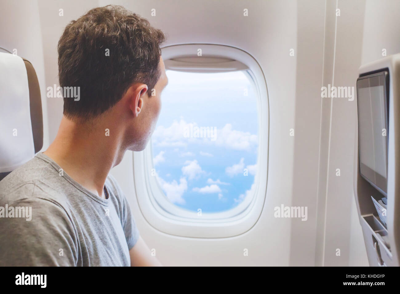 Viaggiatore passeggero guardando alla finestra in aereo, viaggi in volo turistico uomo seduto in aereo Foto Stock