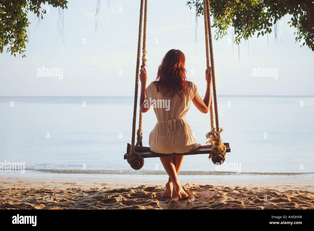 Bella donna attraente seduto sulla rotazione sulla estate tropicale spiaggia soleggiata, sogno concetto di psicologia Foto Stock