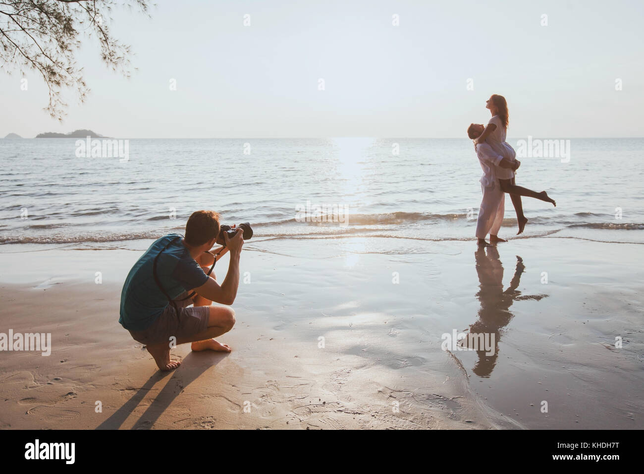 Matrimonio e stile di vita fotografo di scattare le foto di affettuosa giovane sulla spiaggia al tramonto Foto Stock