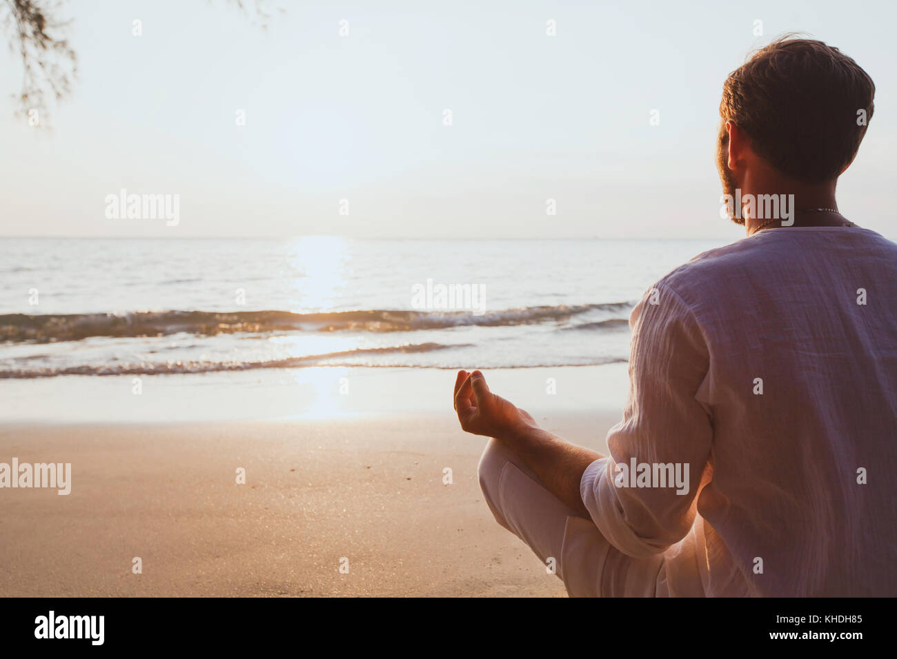 La meditazione, l'uomo la pratica dello yoga a Sunset beach, con uno sfondo con spazio di copia Foto Stock