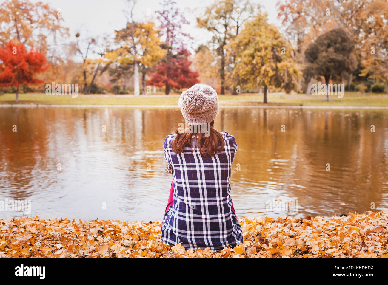 Bella giovane donna seduta in autunno foresta vicino lago, caduta stagione la natura intima sfondo hygge Foto Stock