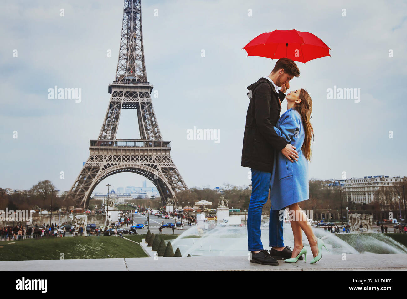 Romantico affettuoso giovane baciare sotto ombrellone vicino alla Torre Eiffel, luna di miele a Parigi Foto Stock