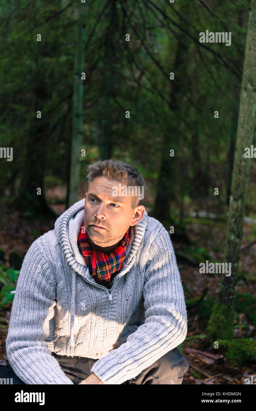 Metà uomo adulto in boschi ritratto di uno stile di vita che indossa il ponticello di maglia e sciarpa rossa che guarda lontano modello di rilascio: Sì. Proprietà di rilascio: No. Foto Stock