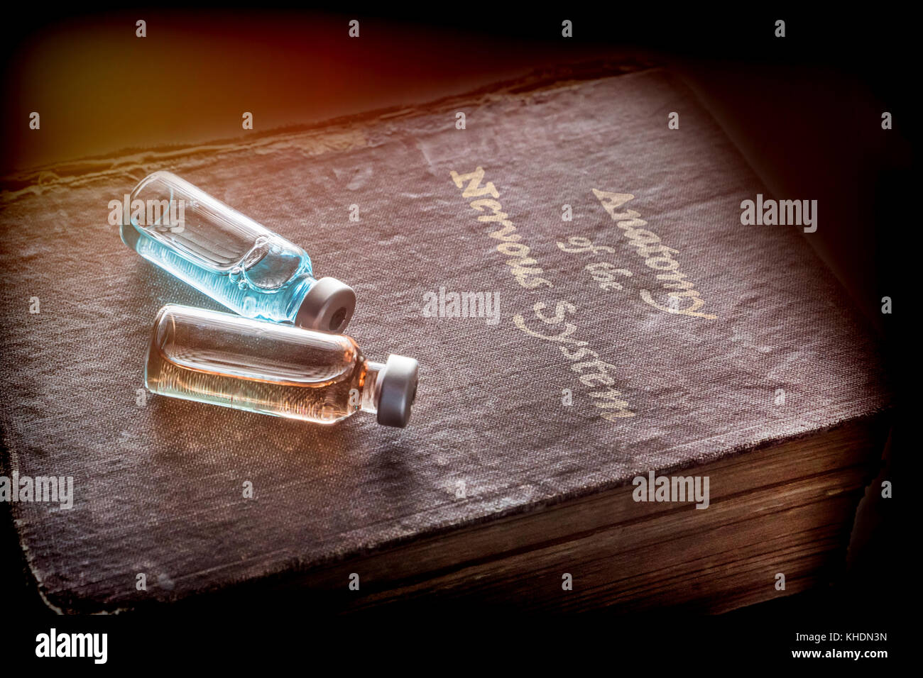 Due fiale di medicina in un antico libro di anatomia del sistema nervoso, immagine concettuale Foto Stock