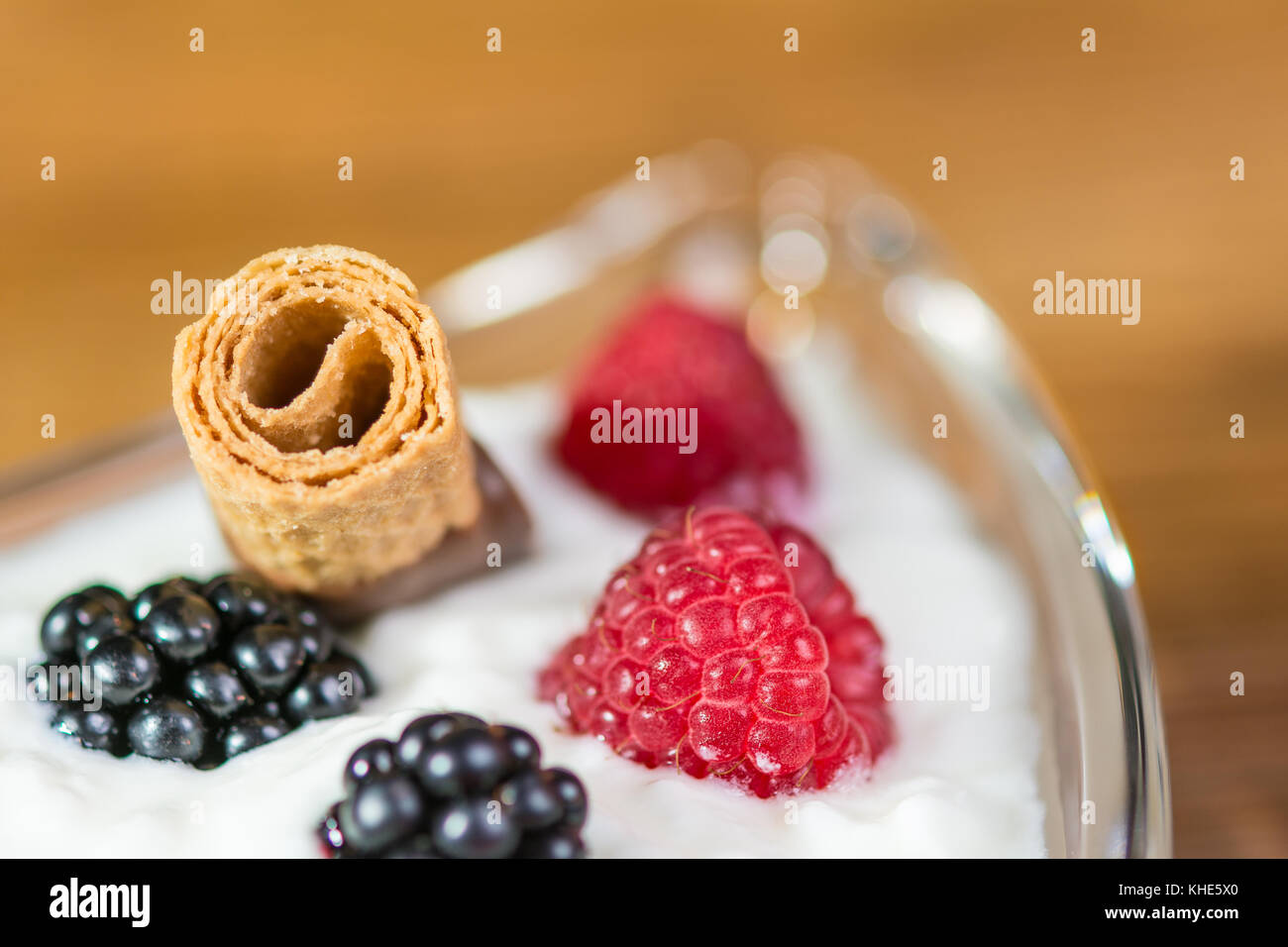 Dessert con frutta fresca e bokeh. dettaglio della ciotola con yogurt, lamponi, more e biscuit su sfondo sfocato. Foto Stock