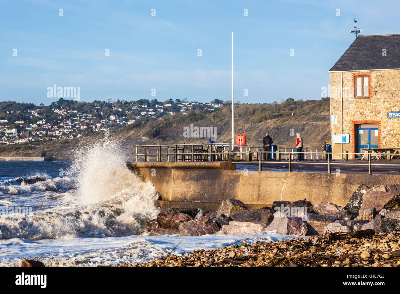 Onde che si infrangono contro la banchina a Charmouth nel Dorset con Lyme Regis in distanza. Foto Stock